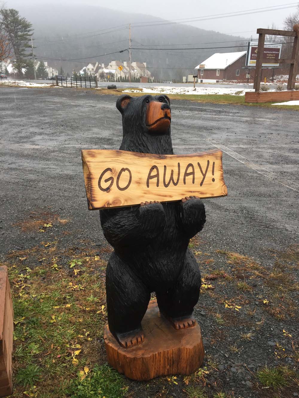 chainsaw carved bear with go away sign